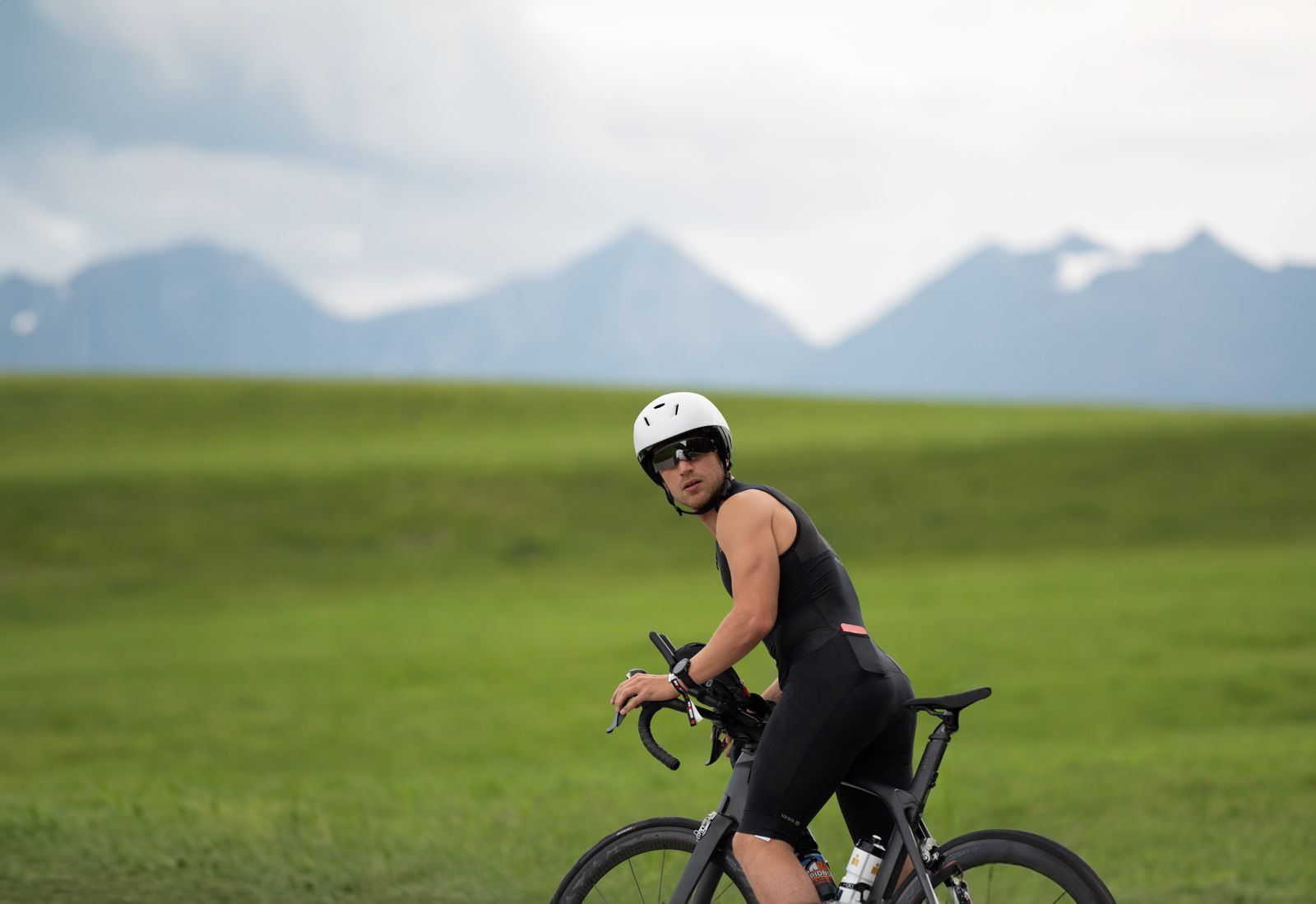 Triathlète en position aérodynamique sur un vélo de contre-la-montre, route de montagne et sommets en arrière-plan